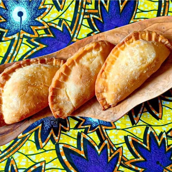 Goudbruine pastechi op een houten schaal met kleurrijke stof